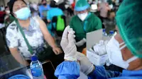 Seorang petugas kesehatan (kanan) bersiap untuk memberikan vaksin virus corona COVID-19 AstraZeneca di klinik vaksinasi massal darurat di Denpasar, Bali, Selasa (6/7/2021). Indonesia tengah memerangi gelombang infeksi baru yang belum pernah terjadi sebelumnya. (SONNY TUMBELAKA/AFP)