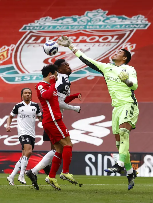 Kiper Fulham Alphonse Areola meninju bola di bawah tekanan dari pemain Liverpool Mohamed Salah pada pertandingan Liga Inggris di Stadion Anfield, Liverpool, Inggris, Minggu (7/3/2021). Liverpool takluk 0-1 dari Fulham. (Phil Noble/Pool via AP)