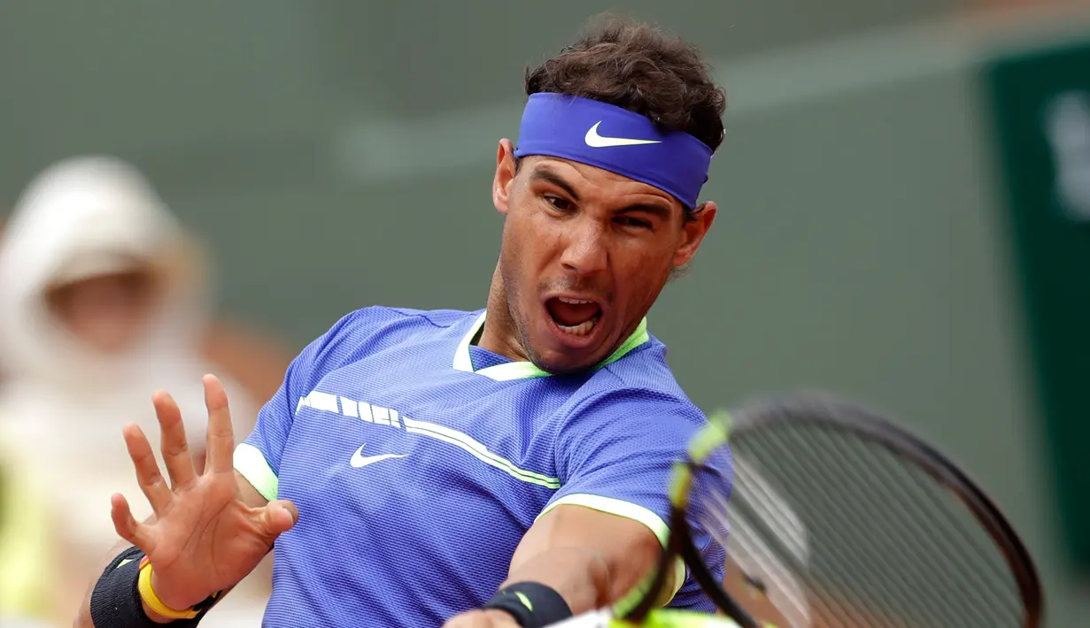 Petenis Spanyol, Rafael Nadal bereaksi saat mengembalikan bola ke petenis Prancis, Benoit Paire pada babak pertama Prancis Terbuka  di Stade Roland Garros, Senin (29/5). Nadal mengalahkan tuan rumah dengan skor 6-1, 6-4, 6-1. (AP Photo/Petr David Josek)