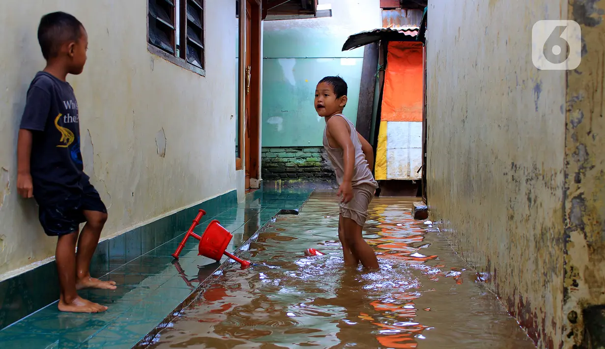 Anak-anak bermain banjir yang melanda kawasan Bidara Cina, Kecamatan Jatinegara, Jakarta Timur, Selasa (25/2/2020). Baru satu hari air surut, kawasan Bidara Cina yang bersebelahan dengan Kali Ciliwung kembali mengalami banjir. (merdeka.com/magang/ Muhammad Fayyadh)