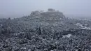 Bukit Acropolis kuno tertutup salju di Athena, Yunani, Senin (24/1/2022). Hujan salju lebat telah mengganggu lalu lintas udara di Athena dan kota tetangga terbesar di Turki, Istanbul, sementara beberapa pulau Aegea dan sebagian besar wilayah Turki diselimuti oleh salju.  (AP Photo/Michael Varaklas)