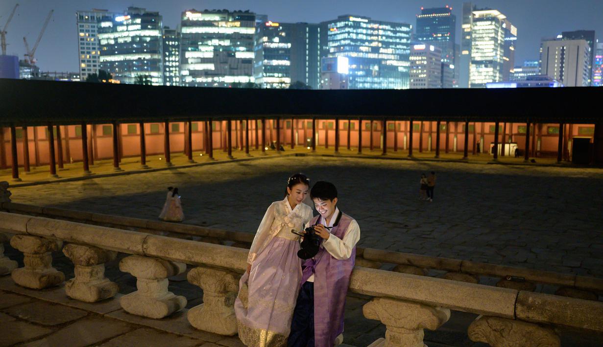 Gambar pada 4 Oktober 2019, wisatawan memainkan kamera mereka saat kunjungan malam ke Istana Gyeongbokgung di pusat Seoul, Korea Selatan. Kunjungan malam tersedia pada minggu ketiga dan keempat setiap bulan mulai dari 26 April sampai 31 Oktober, kecuali pada bulan Agustus. (Photo by Ed JONES / AFP)