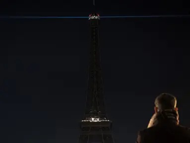 Seorang pria mengambil gambar lampu Menara Eiffel yang dipadamkan sementara di Paris, Rabu (14/12). Lampu Menara Eiffel dimatikan untuk menunjukkan dukungan bagi warga Aleppo di Suriah. (AFP PHOTO/PHILIPPE LOPEZ)
