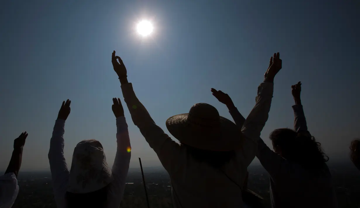 Sejumlah warga mengangkat tangan selama upacara menyambut fenomena equinox di depan Piramida Matahari, Teotihuacan, Meksiko, Senin (20/3). Fenomena equinox merupakan peristiwa ketika matahari tepat berada di atas khatulistiwa. (AP/Rebecca Blackwell)