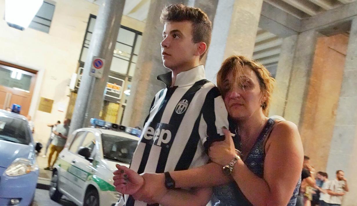 Seorang anak tampak menolong ibunya usai terjadi ledakan saat nonton bareng final Liga Champions di Piazza San Carlo, Turin, Sabtu (3/6/2017). Acara nobar dipadati sekitar 20.000 supporter Juventus. (EPA/Brian Schulz)