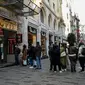 Orang-orang menunggu di luar agen penukaran mata uang dekat alun-alun Taksim ketika lira Turki terperosok ke level terendah sepanjang sejarah di Istanbul, Senin (25/10/2021). Lira melemah imbas pengusiran duta besar AS dan sembilan negara Barat lainnya oleh Presiden Tayyip Erdogan. (Ozan KOSE/AFP)