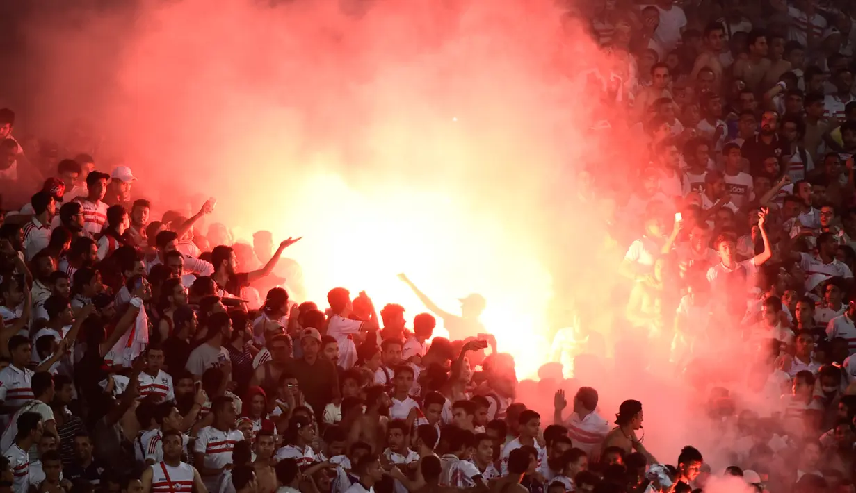 Suporter menyalakan suar saat pertandingan antara klub Mesir, Zamalek dan klub Libya, Al Ahly Tripoli pada lanjutan Grup B Liga Champion Afrika di Army Stadium, Alexandria, Mesir, (9/7). (AFP Photo/Khaled Desouki)