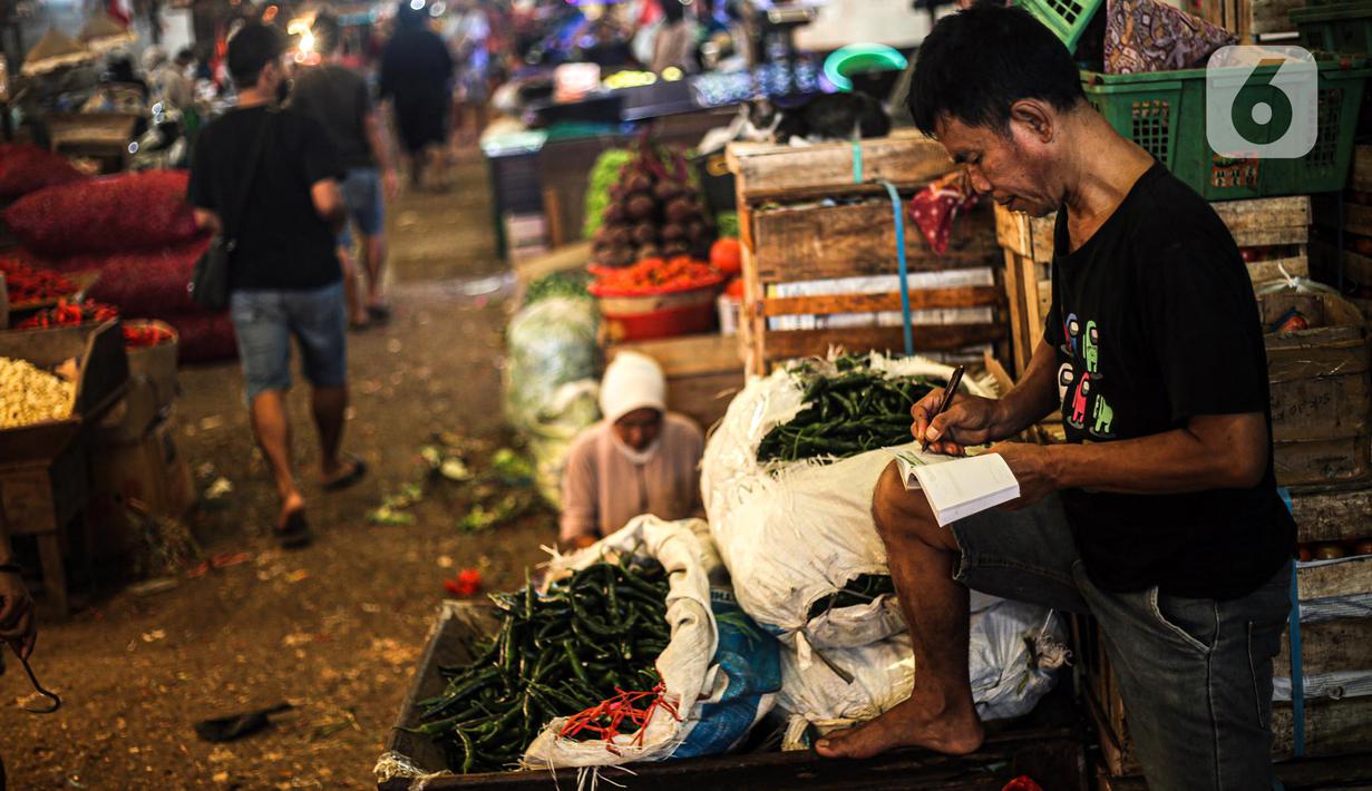 Pedagang menulis pada kertas di Pasar Induk Kramat Jati, Jakarta, Kamis (29/12/2022). Selama revitalisasi, pedagang akan ditempatkan pada lokasi sementara di sekitar pasar. (Liputan6.com/Faizal Fanani)