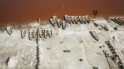 Pemandangan arial ini menunjukkan deretan perahu yang digunakan untuk memanen garam di Danau Retba (Danau Merah Muda) di Senegal pada 16 Maret 2021. Kandungan garam Danau Reba sangat tinggi, yakni 40 persen, bersaing dengan Laut Mati, bahkan bisa melampauinya ketika musim kering. (MARCO LONGARI/AFP)