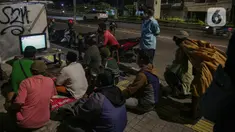 Sejumlah warga menyaksikan pertandingan laga final leg pertama Piala AFF 2020 antara Indonesia melawan Thailand melalui televisi di sejumlah tempat di kawasa Jakarta, Rabu (29/12/2021). Timnas Indonesia harus kalah dengan skor 0-4 atas Thailand. (Liputan6.com/Faizal Fanani)
