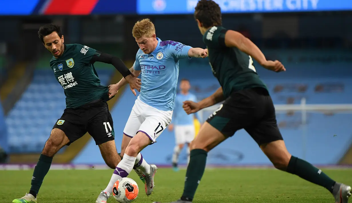 Gelandang Manchester City, Kevin De Bruyne (tengah) berusaha menggiring bola dari kawalan pemain Burnley, Dwight McNeil (kiri) pada pertandingan lanjutan Liga Inggris di Stadion Etihad di Manchester, Inggris (22/6/2020). City menang telak 5-0 atas Burnley. (Michael Regan/POOL/AFP)