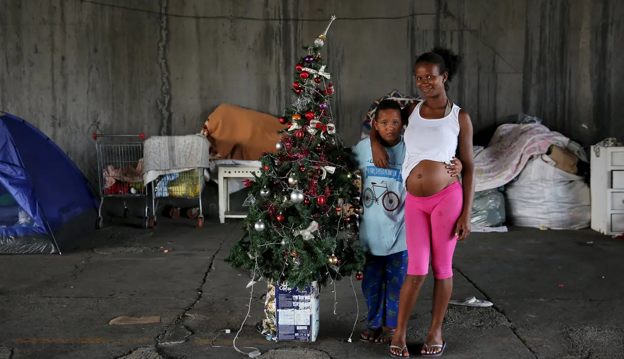 Tatiani (kanan) dan anaknya Leonardo berpose disamping pohon Natal di Sao Paulo, Brasil, (18/12). Mereka adalah keluarga tunawisma yang tinggal di bawah jembatan. (REUTERS/Nacho Doce)