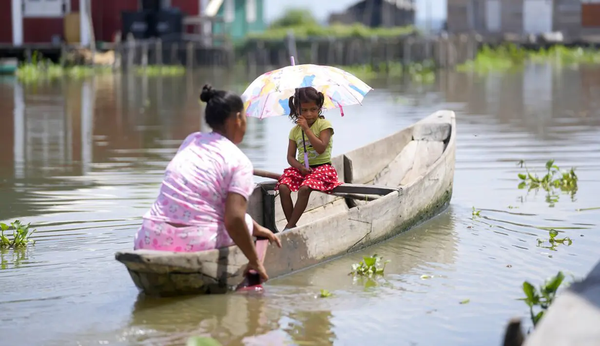 Seorang wanita mendayung sampan bersama putrinya di Cienaga Grande de Santa Marta, Nueva Venecia, Kolombia, 12 Oktober 2021. Sekitar 400 keluarga tinggal di rumah panggung di Cienaga Grande. (AP Photo/Fernando Vergara)