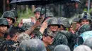 Rodrigo Duterte dipayungi berjalan ditengah para tentara untuk mengumumkan pembebasan kota Marawi di Filipina (17/10). Usai pertempuran selama lima bulan, Duterte mendeklarasikan pembebasan Kota Marawi. (AP Photo/Bullit Marquez)
