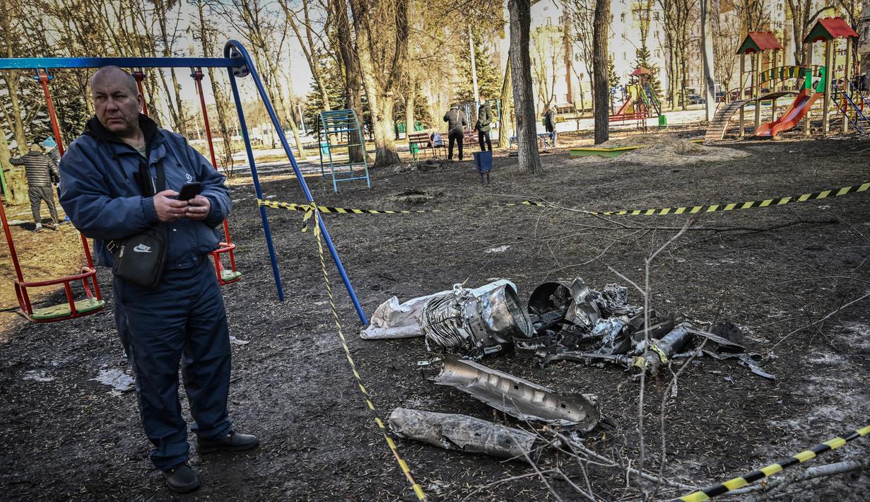 Seorang pria berdiri di samping sisa-sisa rudal di Kota Kharkiv, Ukraina timur, 24 Februari 2022. Angkatan bersenjata Rusia melancarkan invasi militer ke Ukraina. (Aris Messinis/AFP)
