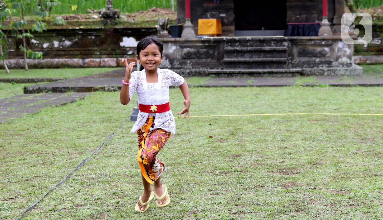 Seorang anak bersiap mengikuti perlombaan usai mengikuti upacara peringatan detik-detik Proklamasi di halaman Tugu Pahlawan Banjar Penglipuran, Kabupaten Bangli, Bali, Kamis (17/8/2023). (Liputan6.com/Helmi Fithriansyah)