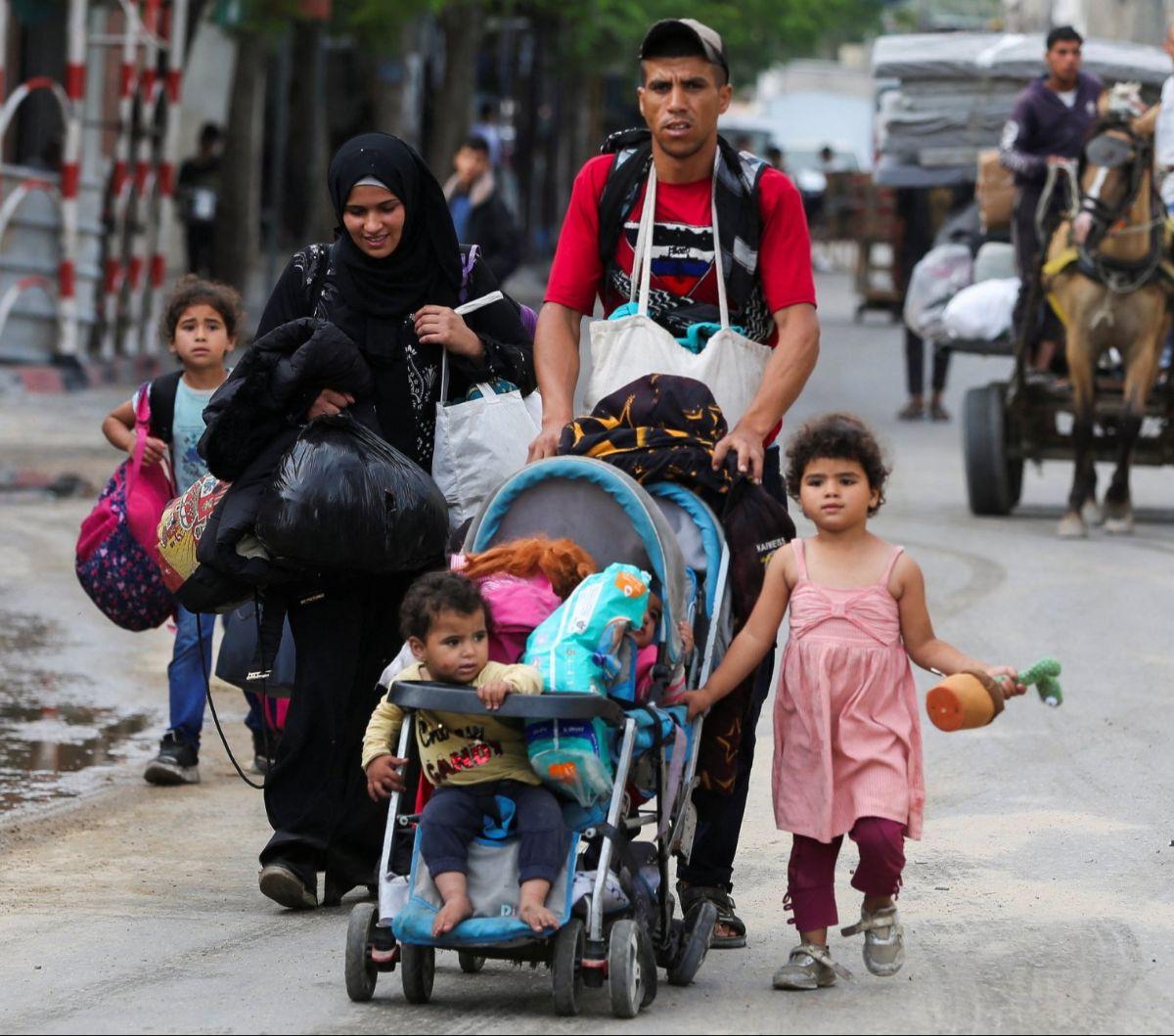 Seorang pria bersama keluarganya membawa barang bawaan saat melarikan diri dari Rafah, Jalur Gaza, Palestina, pada Selasa (28/5/2024). Serangan biadab Israel yang menghantam kamp pengungsian di Rafah membuat warga Jalur Gaza ketakutan.&nbsp;Foto: REUTERS/