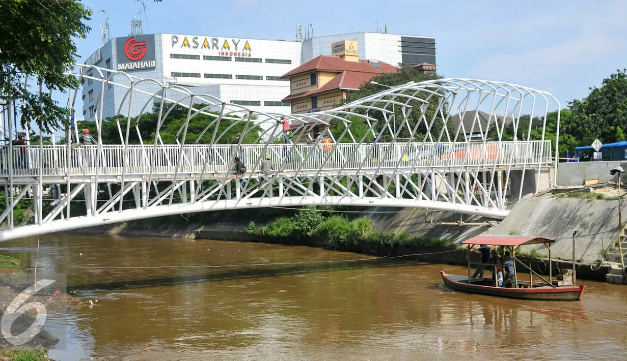 Jembatan penyeberangan dibangun di atas Sungai Ciliwung, Jakarta, Senin (4/4). Jembatan itu untuk mempermudah warga menyeberang dan rencaanya akan siap digunakan pada 6 April mendatang. (Liputan6.com/Yoppy Renato)
