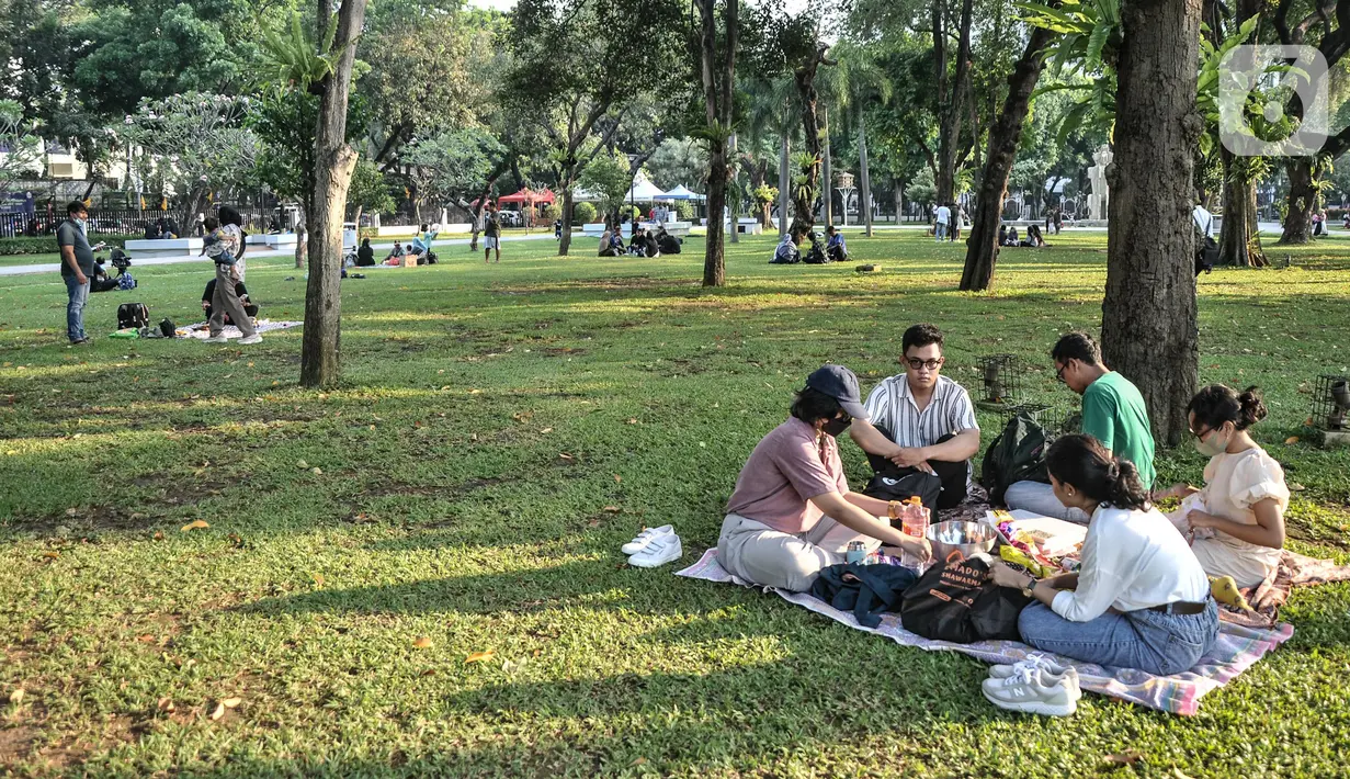 Warga menyantap makanan saat berkunjung ke Lapangan Banteng, Jakarta Pusat, Minggu (19/6/2022). Sejak kembali dibuka usai pandemi COVID-19 mereda, Lapangan Banteng kian ramai didatangi warga Jakarta dan menjadi salah satu lokasi wisata alternatif untuk menghabiskan waktu bersama keluarga serta sarana olahraga. (merdeka.com/Iqbal S. Nugroho)
