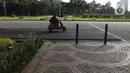 Pengunjung melewati contoh aspal lintasan Formula E di Monas, Jakarta, Minggu (23/2/2020). Aspal untuk sirkuit Formula E di uji coba di Monas, lokasi pengaspalan itu berada di Monas bagian timur. Pengaspalan dilakukan dengan dua metode, sandsheet dan geotextile. (Liputan6.com/Herman Zakharia)