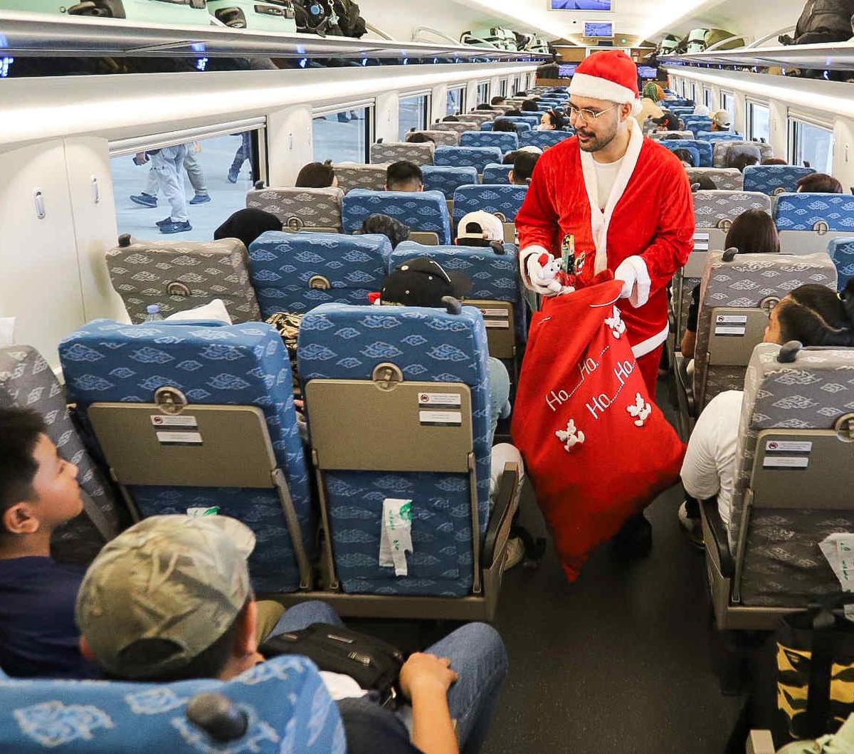Petugas berkostum Sinterklas menyapa membagikan hadiah kepada penumpang kereta cepat Whoosh di Stasiun Kereta Cepat Halim, Jakarta, Minggu (24/12/2023). Dalam rangka menyambut Natal 2023, KCIC menghadirkan Sinterklas untuk menghibur para penumpang.&nbsp;<