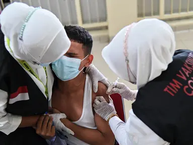 Reaksi seorang siswa SMA saat menerima dosis vaksin virus corona COVID-19 Pfizer di Rumah Sakit Zainoel Abidin, Banda Aceh, Aceh, Selasa (9/11/2021). Vaksinasi COVID-19 di kalangan warga Kota Banda Aceh tembus 80 persen. (CHAIDEER MAHYUDDIN/AFP)
