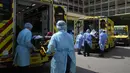 Pekerja medis yang mengenakan pakaian pelindung memindahkan pasien dari ambulans ke rumah sakit di Hong Kong, Jumat (4/3/2022). Pemimpin Hong Kong awal pekan ini mengatakan mobilitas orang mungkin dibatasi selama tes covid-19 massal wajib ketika kasus harian mencapai rekor. (AP Photo/Kin Cheung)