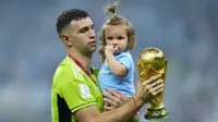 Tak mau ketinggalan, sang penjaga gawang peraih Golden Glove, Emiliano Martinez juga membawa sang buah hati ke stadion dan berfoto bersama trofi Piala Dunia yang baru diraihnya. (AP Photo/Natacha Pisarenko)