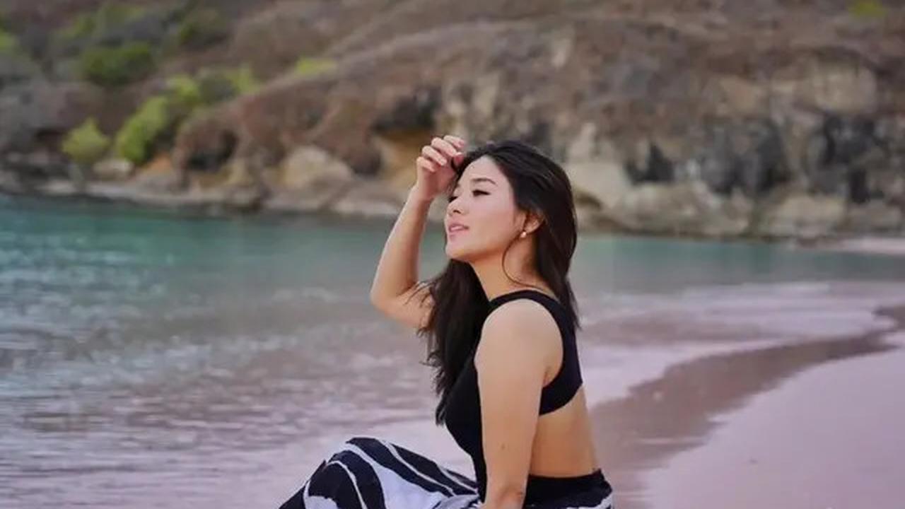 Di Pantai Pink, Naysilla Mirdad mengenakan swimsuit hitam yang dipadukan dengan kain putih berpolakan hitam.&nbsp;