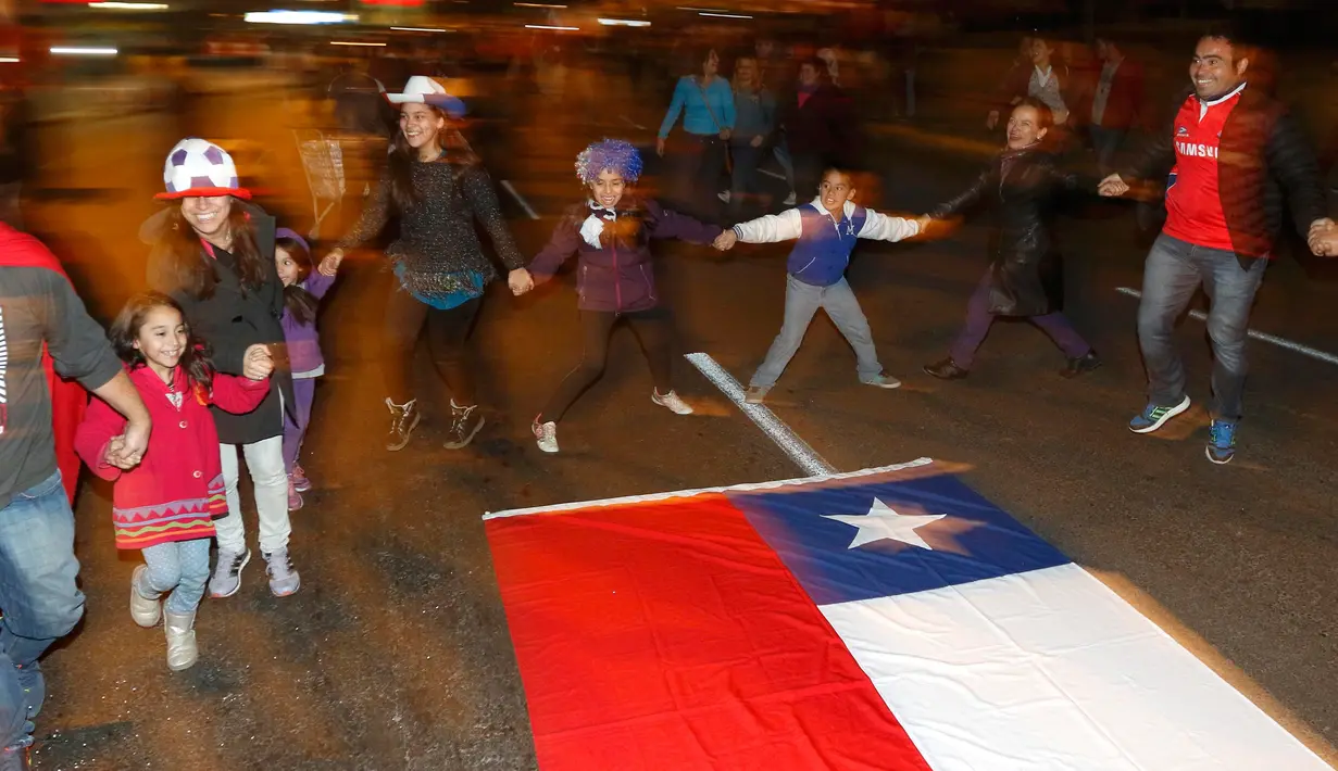 Sejumlah suporter berputar mengelilingi bendera nasional Chili merayakan kemenangan Chili atas Argentina di Copa Amerika 2015 di Santiago, (4/7/2015). Chili menang lewat adu penalti atas Argentina dengan skor 4-1. (REUTERS/Rodrigo Garrido)