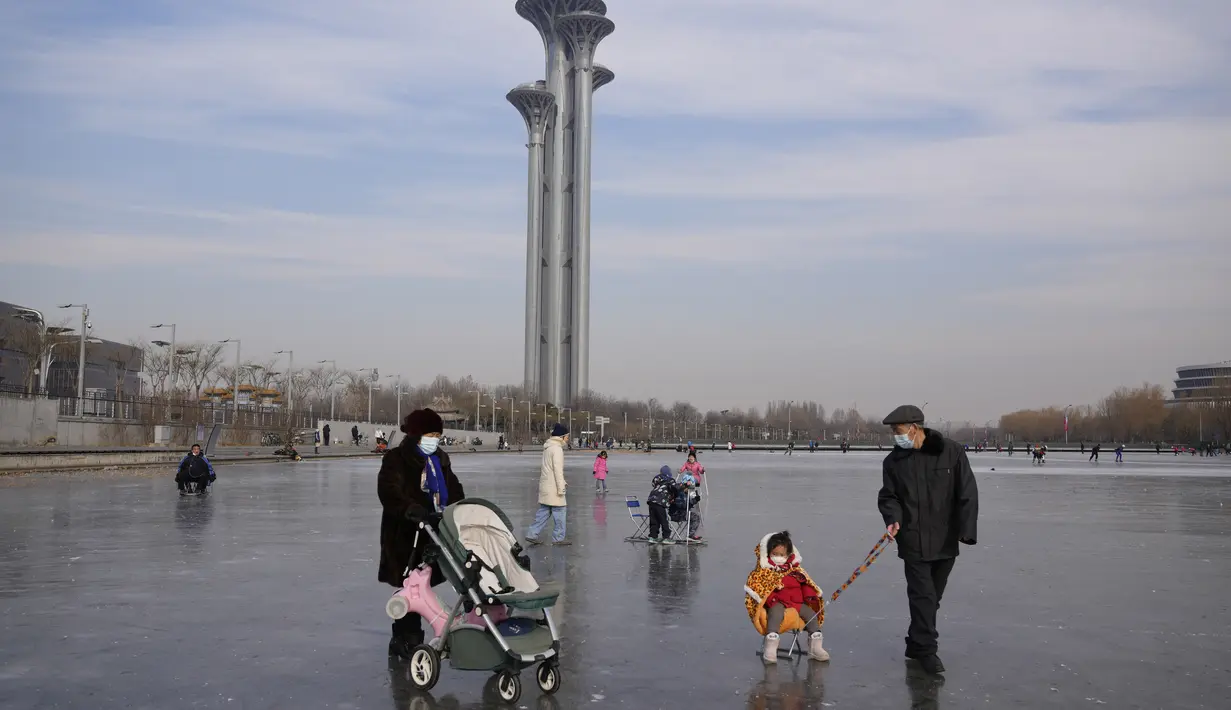 Warga menyeberangi kolam beku di dekat Menara Olimpiade Beijing di Beijing, China (18/1/2022). China telah mengunci sebagian distrik Haidian Beijing menyusul deteksi tiga kasus, hanya beberapa minggu sebelum menjadi tuan rumah Olimpiade Musim Dingin. (AP Photo/Ng Han Guan)