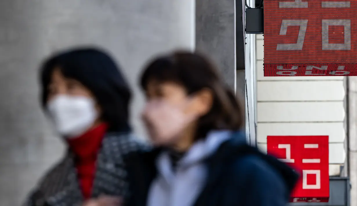 Pejalan kaki berjalan di depan toko Uniqlo yang dioperasikan oleh Fast Retailing Jepang di Tokyo, Rabu (11/1/2023). Peritel dan pemasok pakaian mode cepat terbesar di Asia ini bergabung dengan bisnis domestik lainnya seperti Nippon Life Insurance dan Suntory Holdings yang menaikkan upah. (Philip FONG / AFP)