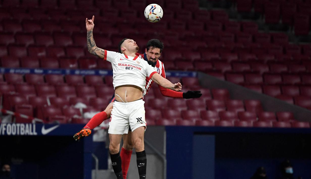 Pemain Atletico Madrid, Stefan Savic, duel udara dengan pemain Sevilla, Lucas Ocampos, pada laga Liga Spanyol di Stadion Wanda Metropolitano, Selasa (12/1/2021). Atletico Madrid menang dengan skor 2-0. (AFP/Pierre-Philippe Marcou)