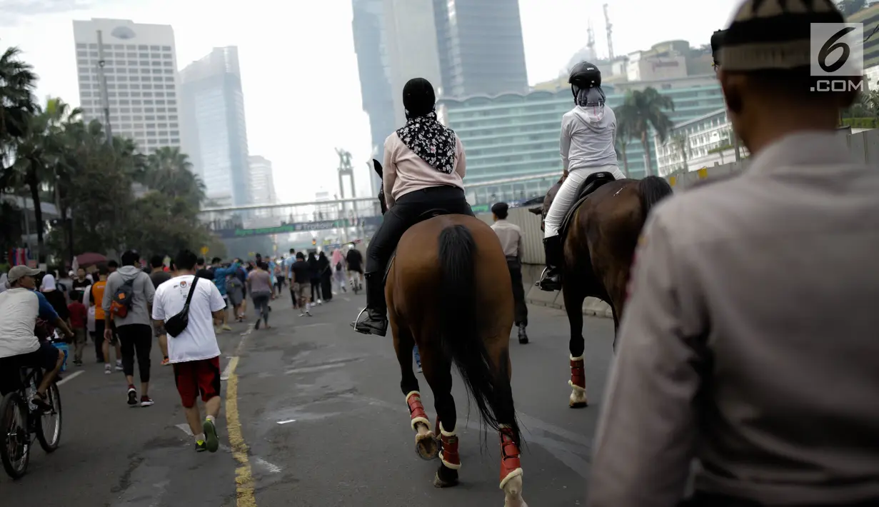 Pengunjung menunggang kuda milik satuan polisi berkuda Polda Metro Jaya di Bundaran HI, Jakarta, Minggu (18/3). Kuda-kuda itu diterjunkan untuk memberi pengenalan terhadap satuan polisi berkuda yang dimiliki Polda Metro Jaya. (Liputan6.com/Faizal Fanani)