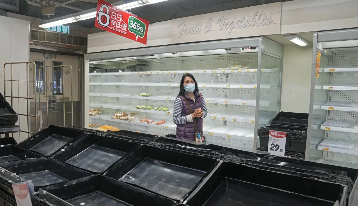 Pengunjung melewati rak-rak kosong dan lemari es saat warga yang panik menimbun makanan di supermarket Hong Kong, Jumat (4/3/2022). Pemimpin Hong Kong awal pekan ini mengatakan mobilitas orang mungkin dibatasi selama tes covid-19 massal wajib ketika kasus harian mencapai rekor. (AP Photo/Kin Cheung)