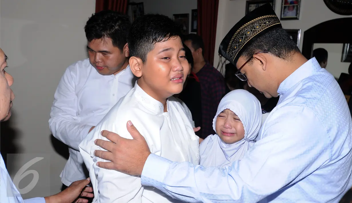 Mendikbud, Anies Baswedan (kanan) menenangkan anak Ketua KPU, Husni Kamil Manik di kompleks KPU, Jakarta, Jumat (8/7). Husni Kamil Manik wafat pada Kamis (7/7) di usia 40 tahun. (Liputan6.com/Helmi Fithriansyah)