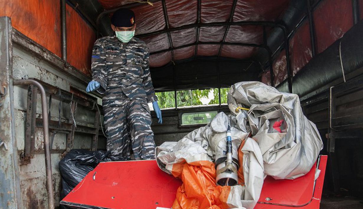 Seorang anggota TNI AL mengangkut barang temuan penumpang AirAsia QZ8501, Bandara Juanda, Rabu (7/1/2015). (AFP Photo/Juni Kriswanto)