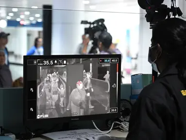 Petugas kesehatan memeriksa 'thermal scanner' untuk mendeteksi suhu tubuh penumpang yang tiba di Bandara Internasional Kuala Lumpur pada Selasa (21/1/2020). Pemerintah Malaysia mulai mengoperasikan alat pemindai suhu tubuh merespons penyebaran virus korona yang kian masif di China. (MOHD RASFAN/AFP)