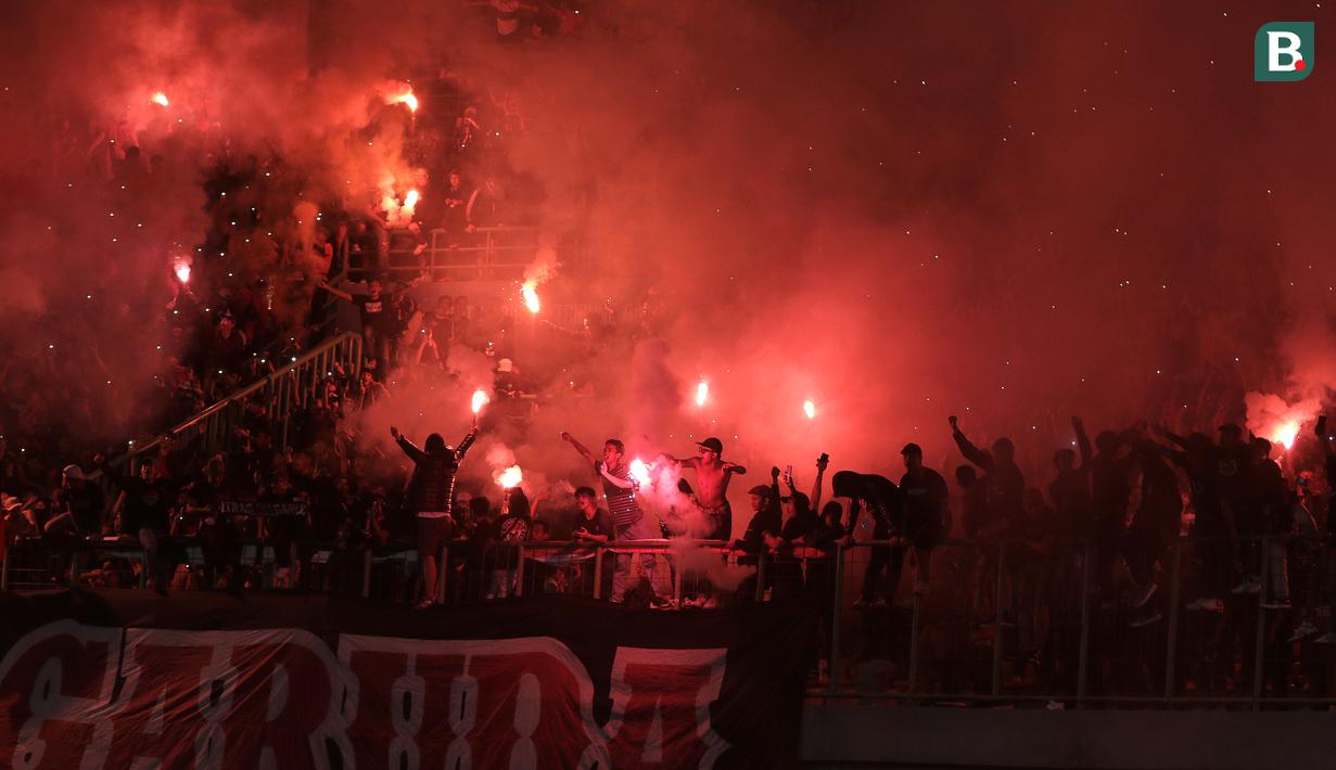 <p>Suporter Timnas Indonesia U-19 menyalakan suar saat laga Grup A Piala AFF U-19 2022 antara Timnas Indonesia U-19 melawan Timnas Vietnam U-19 di Stadion Patriot Candrabhaga, Bekasi, Jawa Barat, Sabtu (02/07/2022). (Bola.com/Ikhwan Yanuar)</p>