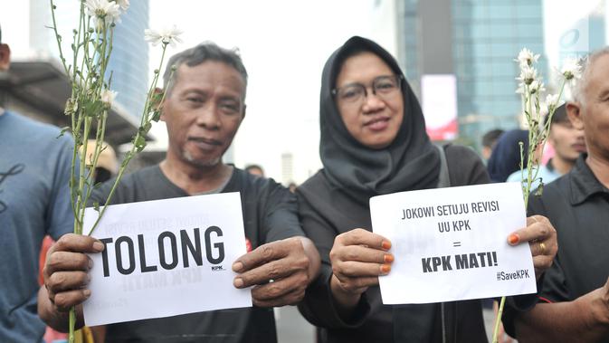 Warga berpose dengan bunga yang diberikan dalam Aksi Selamatkan KPK di hari bebas kendaraan bermotor kawasan Bundaran HI, Jakarta, Minggu (8/9/2019). (merdeka.com/Iqbal S. Nugroho)