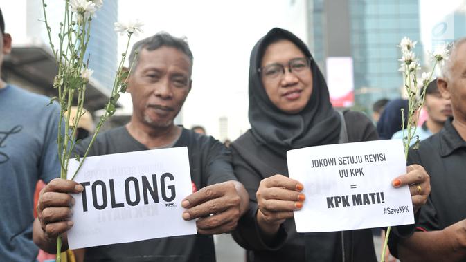 Warga berpose dengan bunga yang diberikan dalam Aksi Selamatkan KPK di hari bebas kendaraan bermotor kawasan Bundaran HI, Jakarta, Minggu (8/9/2019). (merdeka.com/Iqbal S. Nugroho)