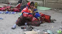 Seorang wanita tunawisma merokok sambil duduk dekat api unggun untuk menghangatkan diri di bawah jembatan layang di Jammu, India, Sabtu (28/12/2019). Sekitar 800 juta orang di India hidup dalam kemiskinan. (AP Photo/Channi Anand)