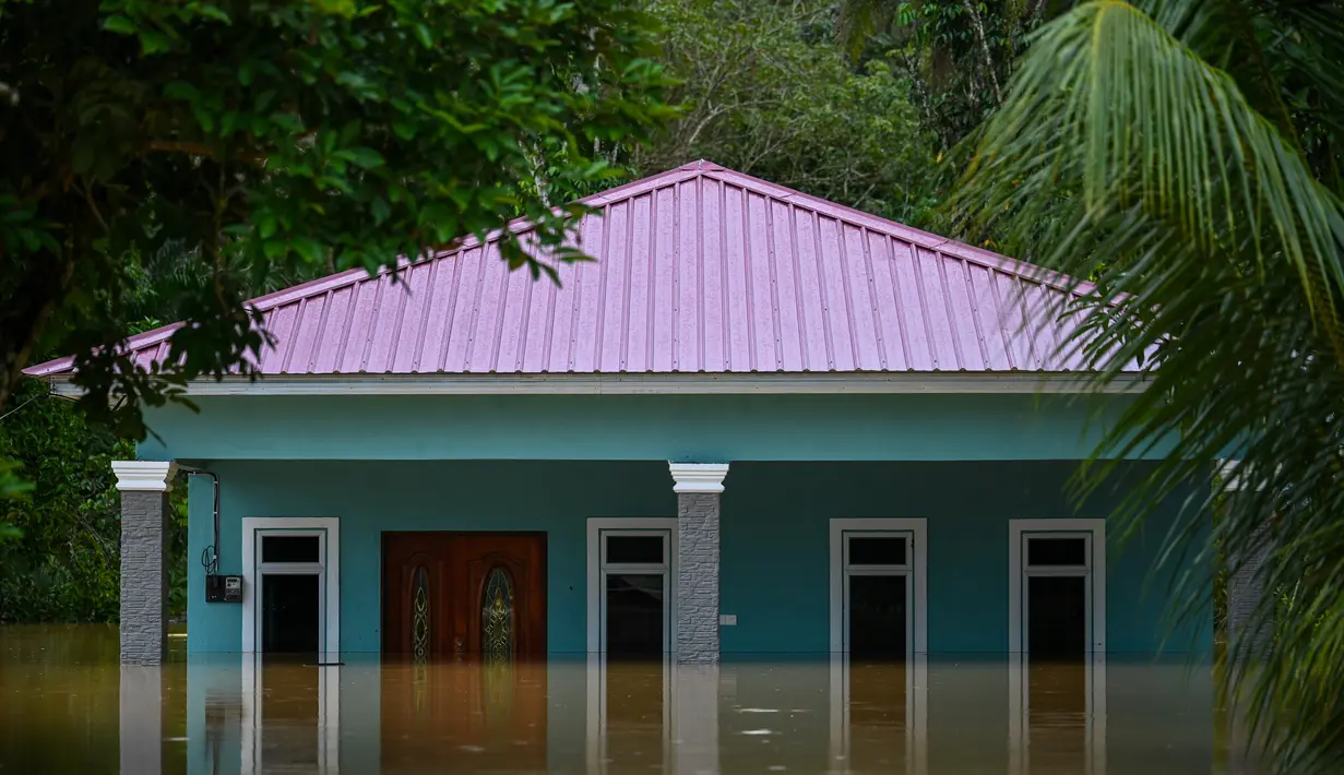 Sebuah rumah terlihat sebagian terendam banjir di Semantan, dekat Lanchang di negara bagian Pahang Malaysia (4/1/2021).  Lebih dari 3.200 orang telah dievakuasi ke pusat-pusat bantuan menyusul banjir yang disebabkan oleh hujan lebat terus menerus sejak Sabtu. (AFP/Mohd Rasfan)