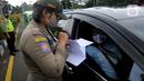 Petugas gabungan memeriksa surat hasil tes cepat antigen terhadap pengendara mobil di Simpang Gadog, Bogor, Kamis (24/12/2020). Pemkab Bogor mewajibkan para wisatawan menunjukkan hasil tes cepat antigen sebagai upaya mencegah penyebaran COVID-19 di saat libur Tahun Baru. (merdeka.com/Arie Basuki)