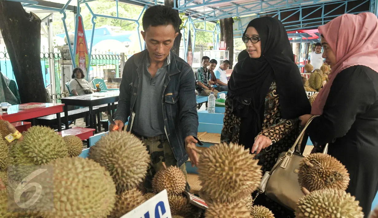 Pedagang durian melayani calon pembeli di Loksem Pusat Penjualan Durian, Jalan TMP Kalibata, Jakarta Selatan, Kamis (9/2). Pemprov DKI Jakarta bangun Loksem Pusat Penjualan Durian di Kalibata. (Liputan6.com/Yoppy Renato)