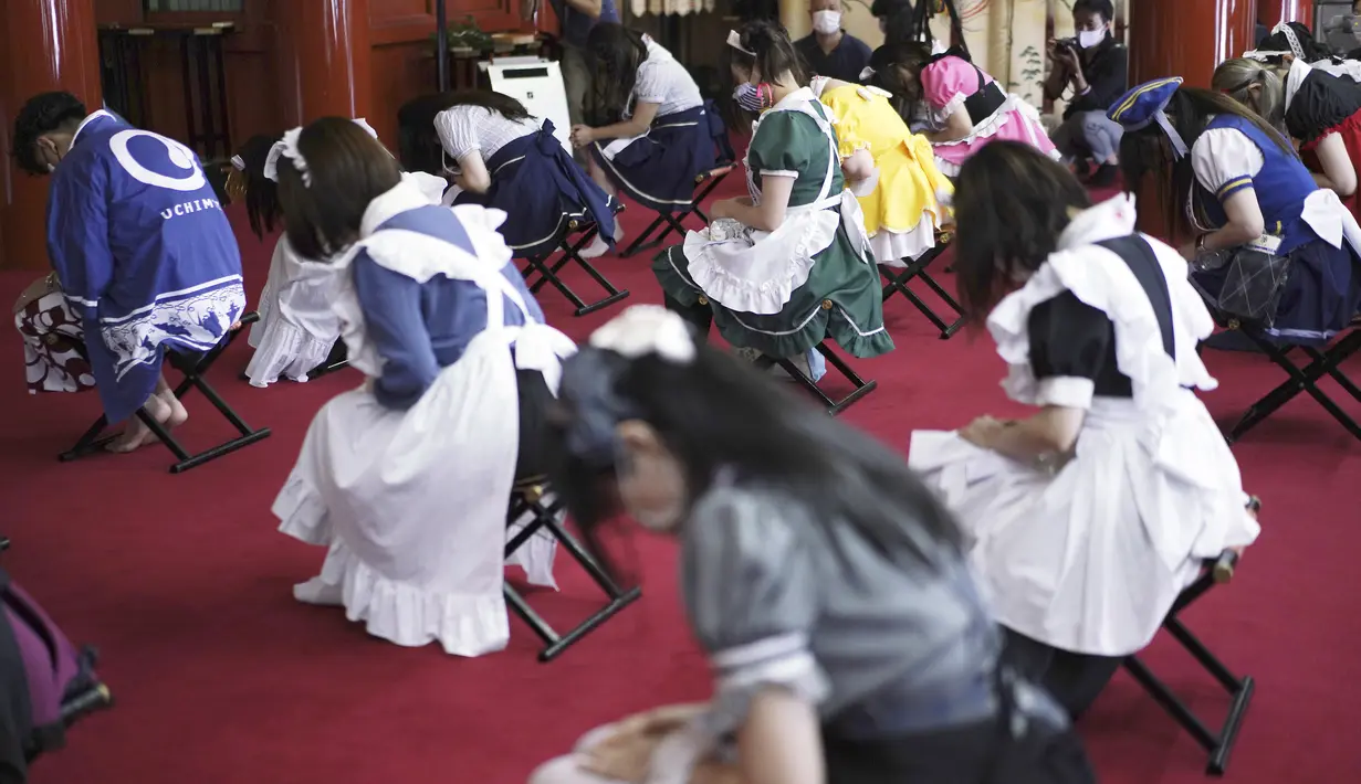 Para karyawan yang mengenakan kostum pelayan dari beberapa kafe bertema pembantu di Akihabara berdoa selama pertemuan doa untuk perlindungan dari COVID-19 dan untuk bisnis yang berkembang pesat di kuil Kanda Myojin, Tokyo (25/7/2020). (AP Photo/Eugene Hoshiko)