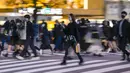 Orang-orang yang memakai masker berjalan di sekitar persimpangan Shibuya Tokyo, Jepang, Senin (29/11/2021). Penutupan pintu untuk warga negara asing ke Jepang hanya  bersifat sementara hingga diperoleh informasi lanjutan tentang varian Omicron. (AP Photo/Kiichiro Sato)