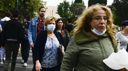 Pejalan kaki, beberapa mengenakan masker, berjalan di Syntagma square, Athena, Selasa (9/11/2021). Yunani mencapai rekor tertinggi kasus Covid-19 selama dua hari berturut-turut. Meski demikian, pemerintah masih mengesampingkan kebijakan lockdown atau penutupan sekolah. (AP Photo/Michael Varaklas)