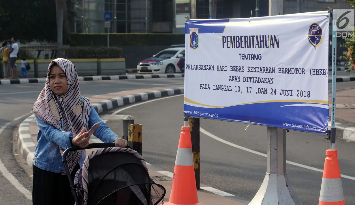 Warga melintasi spanduk pemberitahuan peniadaan pelaksanaan Hari Bebas Kendaraan Bermotor (HBKB) di sekitar Bundaran Hotel Indonesia, Jakarta, Minggu (3/6). Pelaksanaan HBKB akan ditiadakan pada 10, 17, dan 24 Juni 2018. (Liputan6.com/Helmi Fithriansyah)