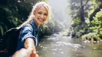 Seorang wanita mengajak pasangannya berjalan menyusuri sungai di pegunungan (Shutterstock/JacobLund).